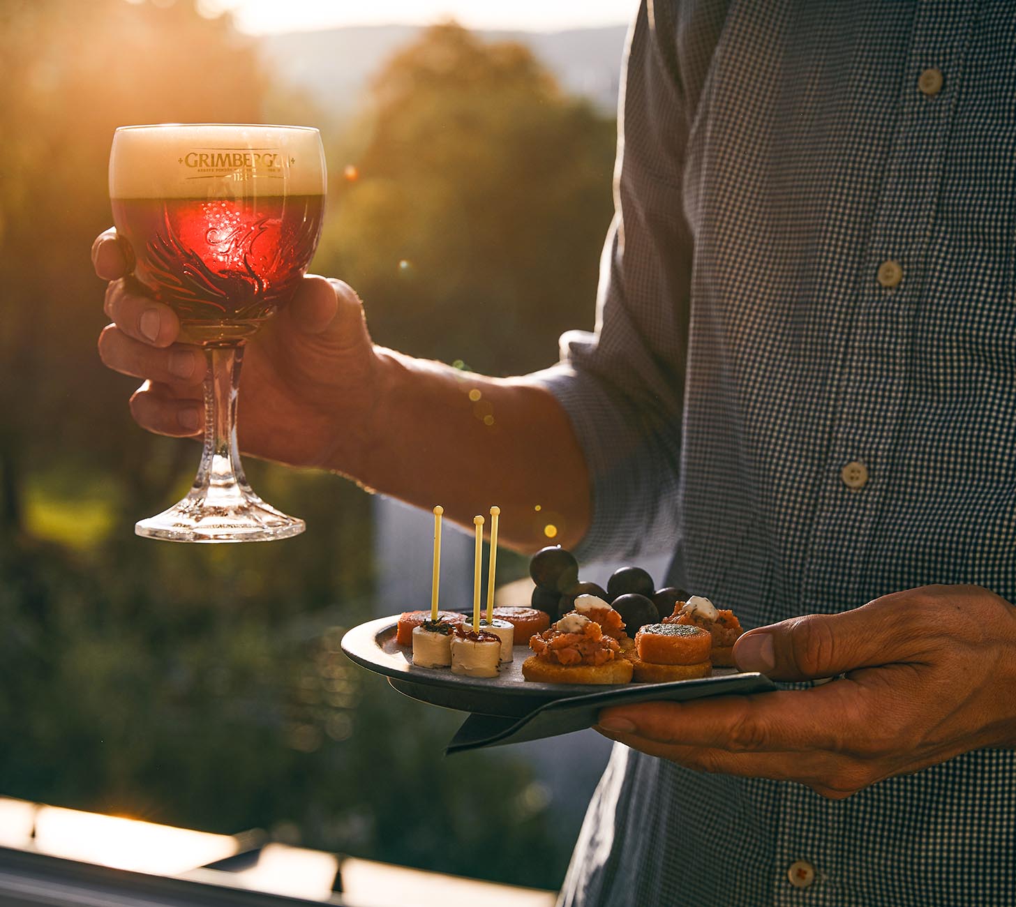 DE: Grimbergen Rouge Bier – rot schimmerndes belgisches Klosterbier im Kelchglas mit Schaumkrone, serviert zu feinen Snacks bei Sonnenlicht.
FR: Bière Grimbergen Rouge – bière rouge d’abbaye belge servie dans un verre calice mousseux accompagnée d’amuse-bouches en lumière du soir.
IT: Birra Grimbergen Rouge – birra rossa d’abbazia belga servita in calice con schiuma e antipasti alla luce del tramonto.