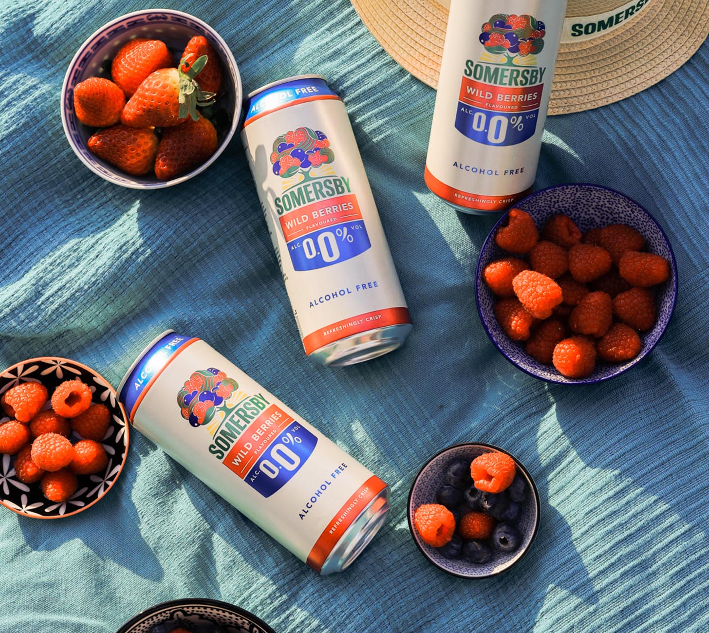 DE: Somersby Wild Berries 0.0% alkoholfrei als sommerliches Moodbild mit frischen Beeren, 50cl Dosen auf blauem Tuch, fruchtige Erfrischung ohne Alkohol.
FR: Somersby Wild Berries 0.0% sans alcool en image d’ambiance estivale avec fruits rouges frais et canettes 50cl, rafraichissant et fruité.
IT: Somersby Wild Berries 0.0% analcolico in mood estivo con frutti di bosco freschi e lattine 50cl, rinfrescante e fruttato.