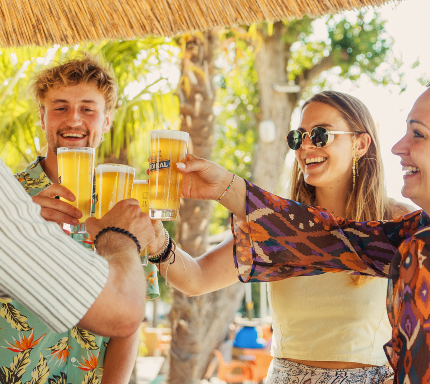 DE: Freundesgruppe prostet sich draussen mit Cardinal Blanche im Stangenglas zu, sommerliche Stimmung.
FR: Groupe d’amis trinquant en plein air avec Cardinal Blanche en verre stange, ambiance estivale.
IT: Gruppo di amici che brinda all’aperto con Cardinal Blanche nel bicchiere stange, atmosfera estiva.