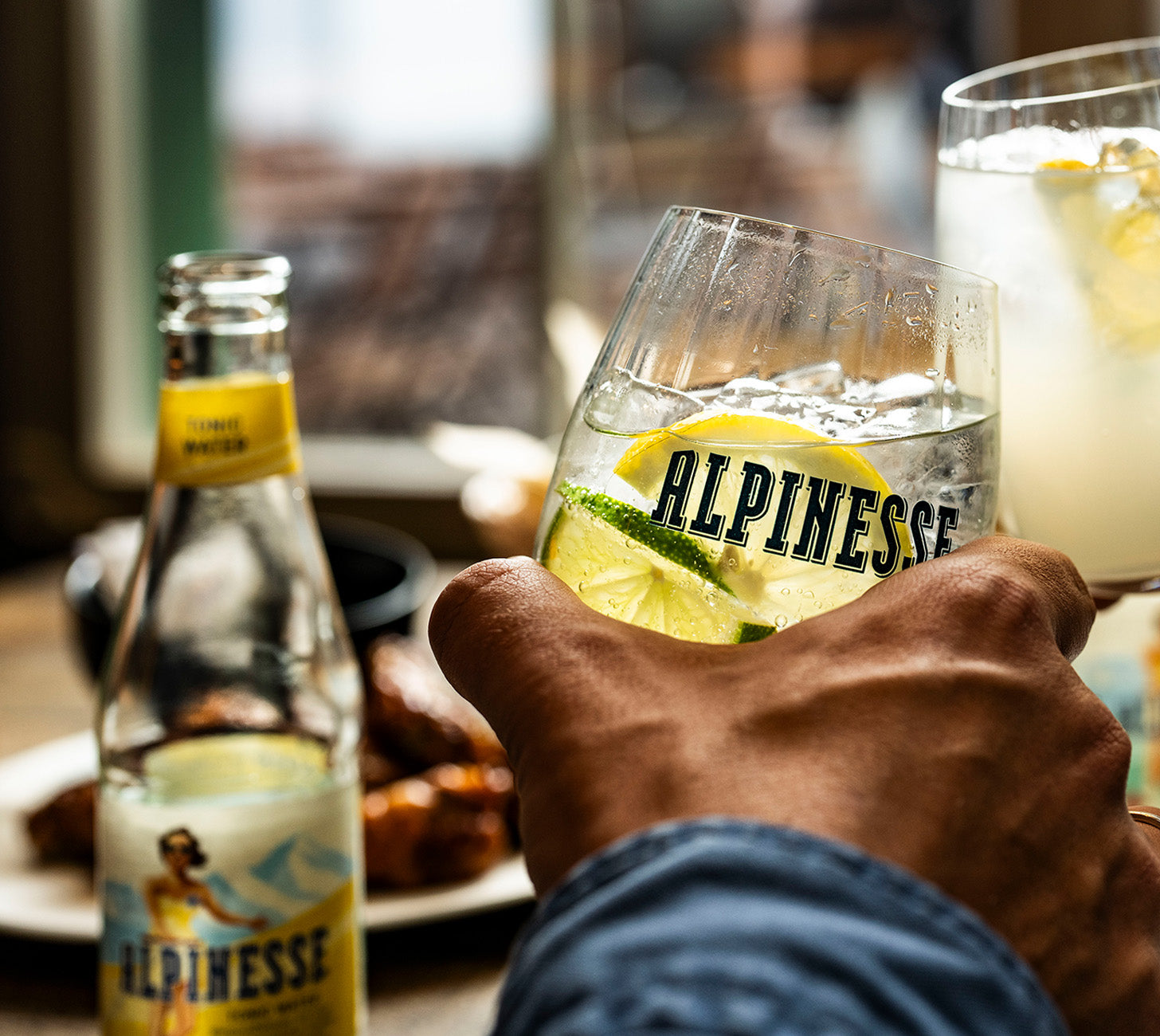 DE: Alpinesse Tonic Water – erfrischendes Tonic im Glas mit Eis und Zitronen-Limetten-Scheiben, serviert in entspannter Atmosphäre.

FR: Alpinesse Tonic Water – tonic rafraîchissant avec glaçons et citron vert, servi dans une ambiance détendue.

IT: Alpinesse Tonic Water – tonica rinfrescante con ghiaccio e fettine di limone e lime, servita in un’atmosfera rilassata.
