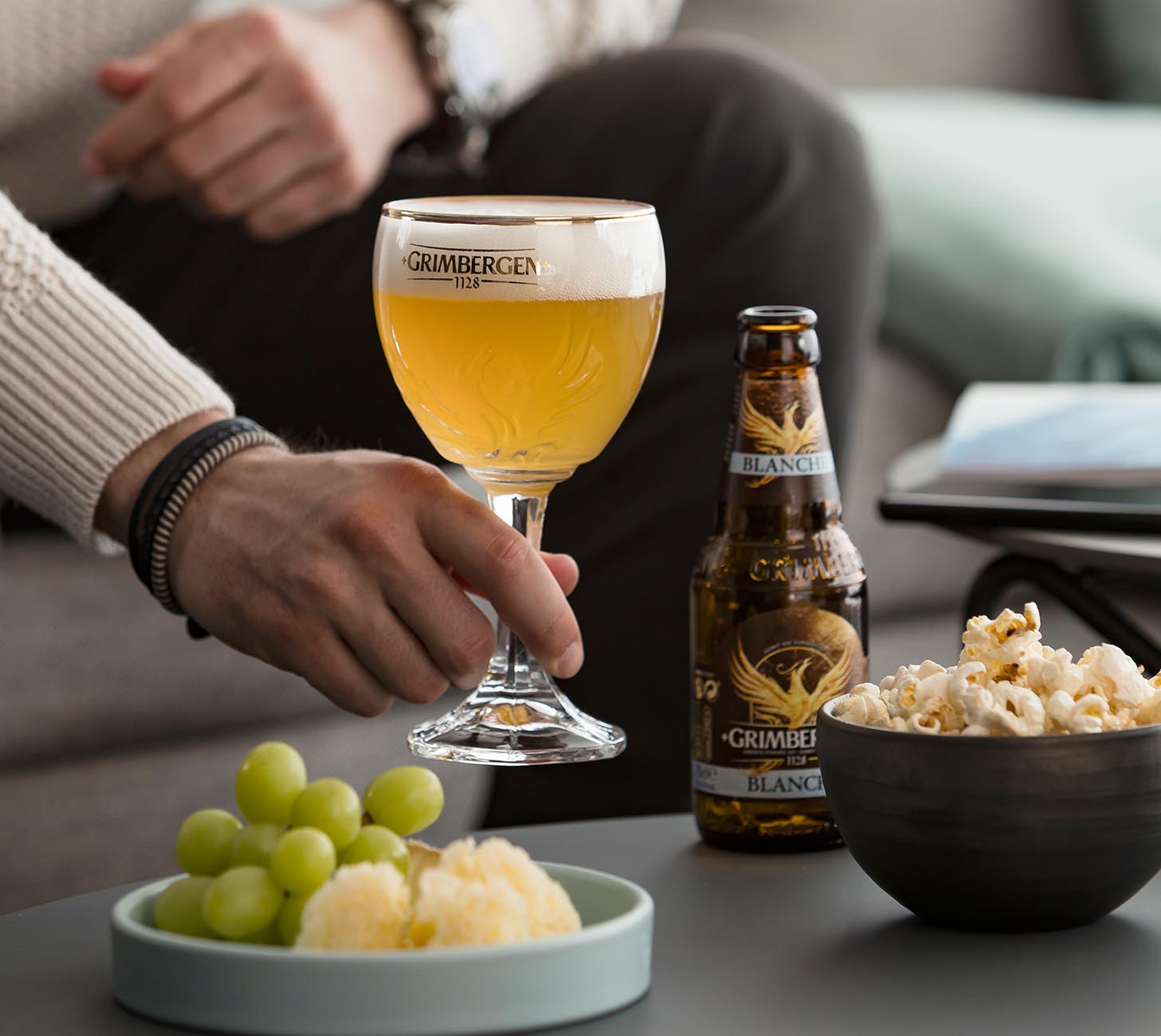 DE: Grimbergen Blanche Bier – hellgoldenes belgisches Witbier im Kelchglas mit cremiger Schaumkrone, serviert in entspannter Atmosphäre mit Snacks.

FR: Bière Grimbergen Blanche – bière blanche dorée servie dans un verre calice avec mousse crémeuse, ambiance détendue avec des en-cas.

IT: Birra Grimbergen Blanche – birra chiara belga servita in calice con schiuma cremosa, atmosfera rilassata con snack.