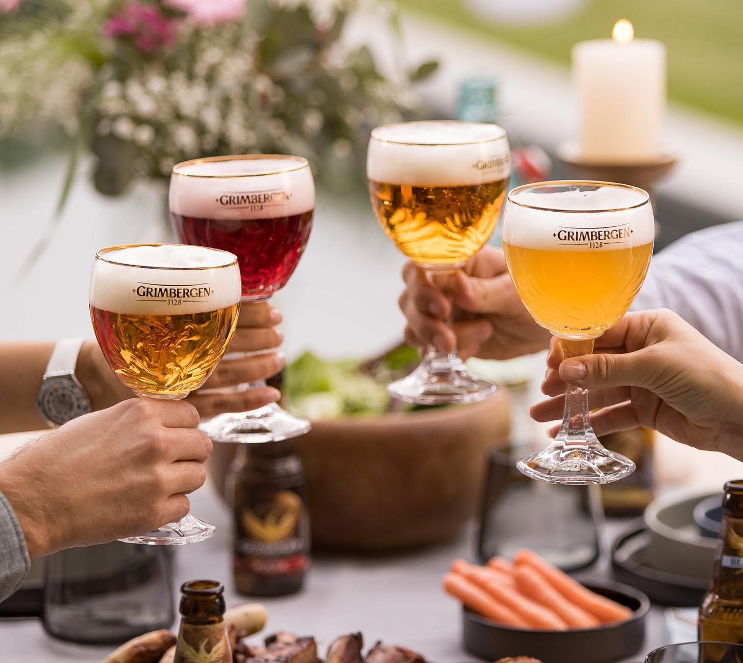 DE: Grimbergen Phoenix Gläser – mehrere stilvolle Bierkelche mit verschiedenen Grimbergen-Biersorten wie Blonde, Ambrée und Rouge, Personen stoßen gemeinsam an in geselliger Stimmung.

FR: Verres Grimbergen Phoenix – plusieurs calices élégants contenant différentes bières Grimbergen, comme Blonde, Ambrée et Rouge, ambiance conviviale de dégustation.

IT: Bicchieri Grimbergen Phoenix – diversi calici eleganti con varie birre Grimbergen come Blonde, Ambrée e Rouge, persone che brindano in atmosfera conviviale