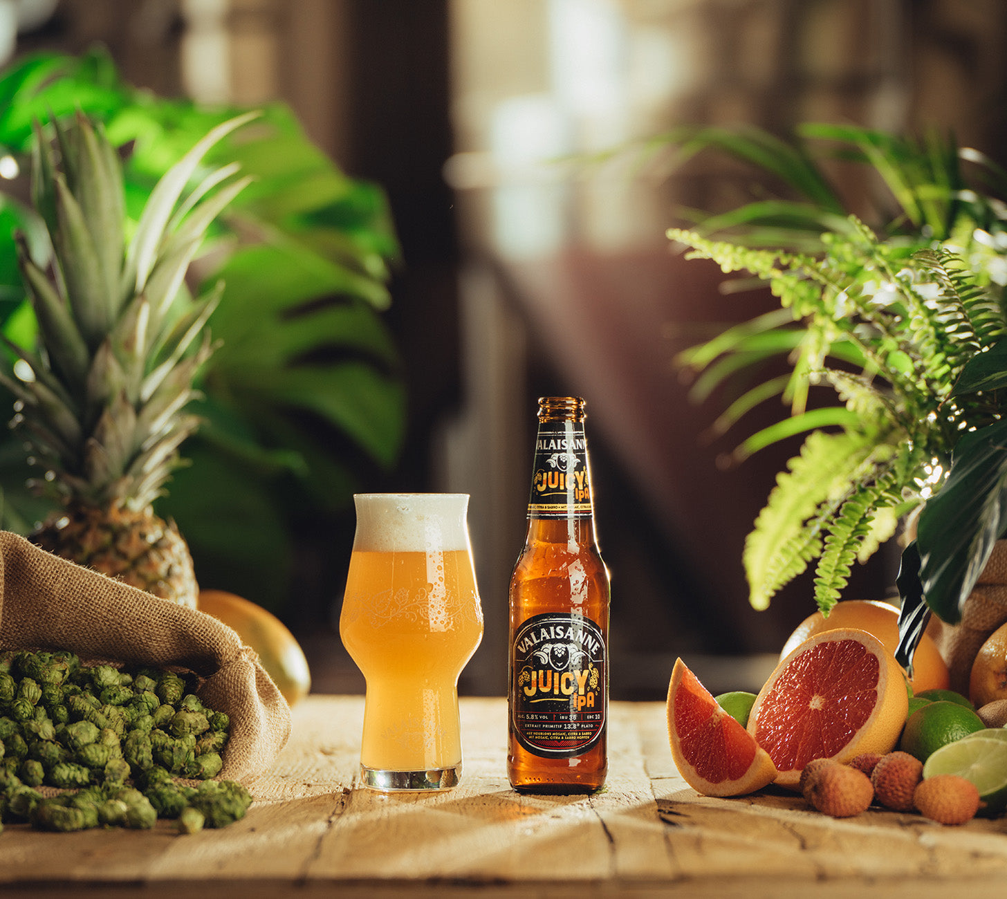 DE: Valaisanne Juicy IPA Flasche in tropischem Ambiente mit Früchten und Glas, stimmungsvolles Genussbild.

FR: Bouteille Valaisanne Juicy IPA dans un décor tropical avec fruits et verre, ambiance gourmande.

IT: Bottiglia Valaisanne Juicy IPA in ambiente tropicale con frutta e bicchiere, scena di degustazione.