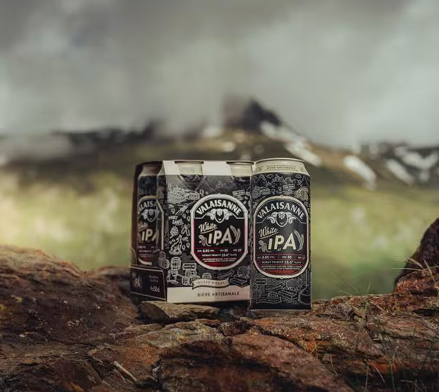 DE: Valaisanne White IPA 50cl – Dose und 4-Pack in natürlicher Berglandschaft, stimmungsvolles Outdoor-Moodbild.

FR: Valaisanne White IPA 50cl – canette et pack dans un décor naturel de montagne, image d’ambiance en extérieur.

IT: Valaisanne White IPA 50cl – lattina e confezione in un paesaggio montano naturale, immagine mood outdoor.