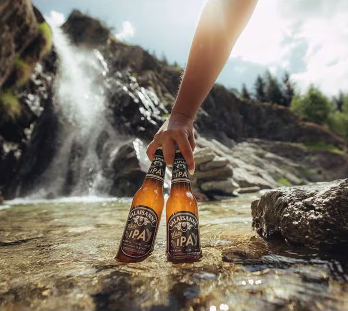 DE: Valaisanne White IPA Flaschen im Outdoor-Setting am Wasser, sommerlich und erfrischend.

FR: Bouteilles Valaisanne White IPA en extérieur près de l’eau, ambiance estivale et rafraîchissante.

IT: Bottiglie Valaisanne White IPA all’aperto vicino all’acqua, atmosfera estiva e rinfrescante.