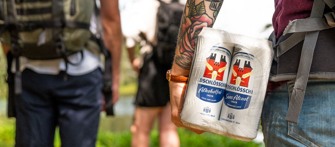 DE: Person hält Feldschlösschen Alkoholfrei Dosen nach einem Outdoor-Event FR: Personne tenant des canettes Feldschlösschen sans alcool après un événement outdoor IT: Persona tiene lattine Feldschlösschen analcolico dopo un evento all'aperto EN: Person holding Feldschlösschen non-alcoholic cans after an outdoor event