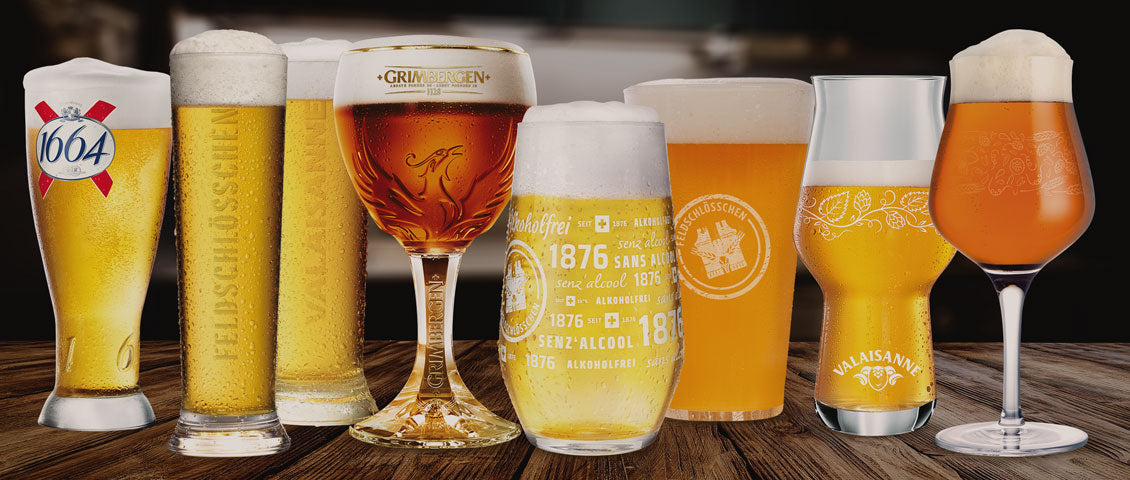 DE: Verschiedene Biergläser mit Grimbergen und Valaisanne Bieren auf Holztisch FR: Différents verres à bière avec bières Grimbergen et Valaisanne sur table en bois IT: Vari bicchieri da birra con birre Grimbergen e Valaisanne su tavolo in legno EN: Various beer glasses with Grimbergen and Valaisanne beers on wooden table