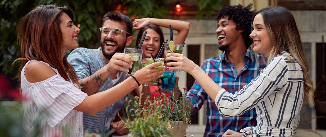 DE: Freundesgruppe stösst mit bunten Cocktails im Freien an FR: Groupe d'amis trinquant avec des cocktails colorés en plein air IT: Gruppo di amici brinda con cocktail colorati all'aperto EN: Group of friends toasting with colourful cocktails outdoors