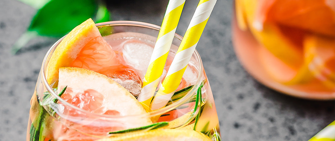 DE: Rosa Apéro-Drink mit Strohhalmen, Gurke und Grapefruit auf hellem Hintergrund FR: Apéro rosé avec pailles, concombre et pamplemousse sur fond clair IT: Drink aperitivo rosato con cannucce, cetriolo e pompelmo su sfondo chiaro EN: Pink aperitif drink with straws, cucumber and grapefruit on light background