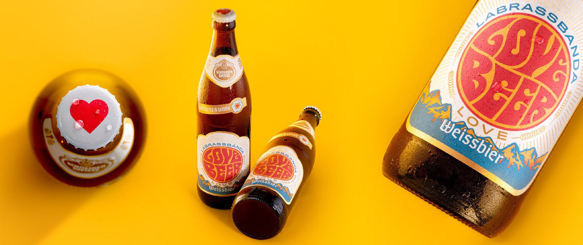DE: Schneider Weisse LoveBeer Flaschen auf gelbem Hintergrund mit Sonnenbrille FR: Bouteilles Schneider Weisse LoveBeer sur fond jaune avec lunettes de soleil IT: Bottiglie Schneider Weisse LoveBeer su sfondo giallo con occhiali da sole EN: Schneider Weisse LoveBeer bottles on yellow background with sunglasses