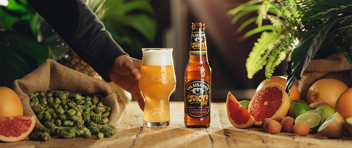 DE: Valaisanne Juicy IPA Flasche und Glas mit Hopfen und Grapefruit auf Holz FR: Bouteille et verre Valaisanne Juicy IPA avec houblon et pamplemousse sur bois IT: Bottiglia e bicchiere Valaisanne Juicy IPA con luppolo e pompelmo su legno EN: Valaisanne Juicy IPA bottle and glass with hops and grapefruit on wood