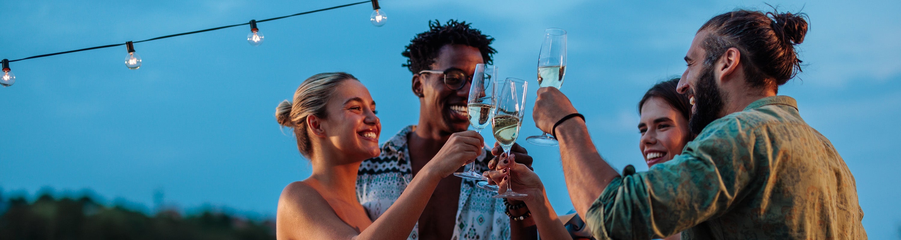 DE: Zwei Personen stossen mit Proseccogläsern an unter blauem Himmel FR: Deux personnes trinquant avec des flûtes de prosecco sous ciel bleu IT: Due persone brindano con flute di prosecco sotto cielo azzurro EN: Two people toasting with prosecco glasses under blue sky