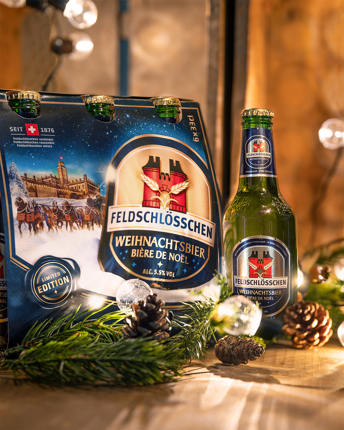 DE: Feldschlösschen Weihnachtsbier 6-Pack und Flasche präsentiert mit passender Weihnachtsdekoration, FR: Pack de 6 et bouteille de Feldschlösschen Bière de Noël présentés avec une décoration de Noël assortie; IT: Confezione da 6 e bottiglia di Feldschlösschen Birra di Natale presentate con decorazioni natalizie abbinate; EN: Feldschlösschen Christmas beer 6-pack and bottle presented with matching Christmas decorations