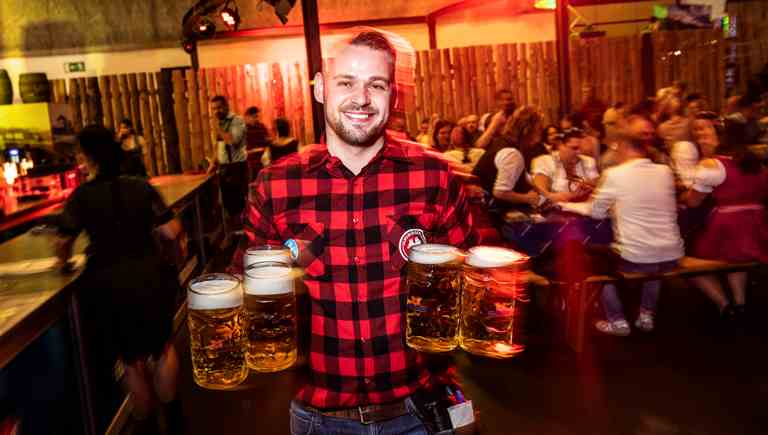 DE: Feldschlösschen Mitarbeiter am Oktoberfest mit 6 Feldschlösschen Bieren in Mass-Gläser; FR: Collaborateur Feldschlösschen à l'Oktoberfest avec 6 bières Feldschlösschen dans des chopes d'un litre; IT: Collaboratore Feldschlösschen all'Oktoberfest con 6 birre Feldschlösschen in boccali da un litro; EN: Feldschlösschen employee at Oktoberfest with 6 Feldschlösschen beers in Mass glasses