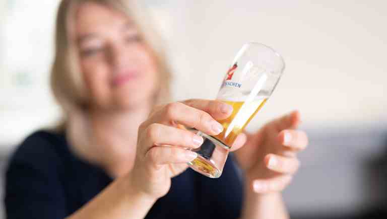 🇩🇪 Frau hält ein Feldschlösschen Bierglas in die Kamera bei der Brauwelt Degustation. 🇮🇹 Donna che tiene un bicchiere di birra Feldschlösschen verso la fotocamera durante la degustazione alla Brauwelt. 🇫🇷 Femme tenant un verre de bière Feldschlösschen vers la caméra lors de la dégustation à la Brauwelt. 🇬🇧 Woman holding a Feldschlösschen beer glass towards the camera during the Brauwelt tasting.